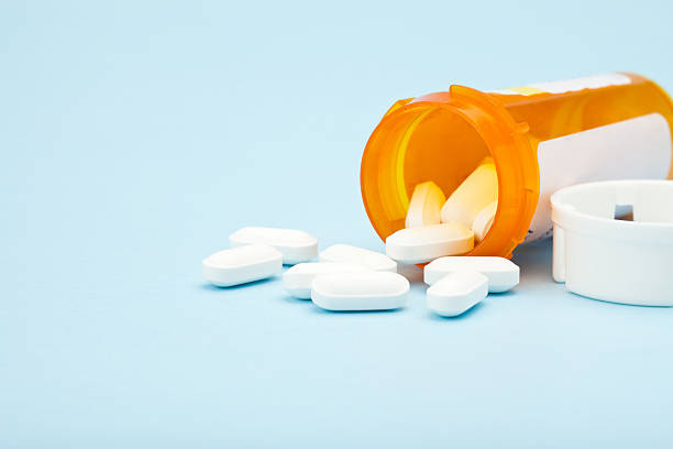 istock Pills spilling out from medicine bottle on blue background 184324262