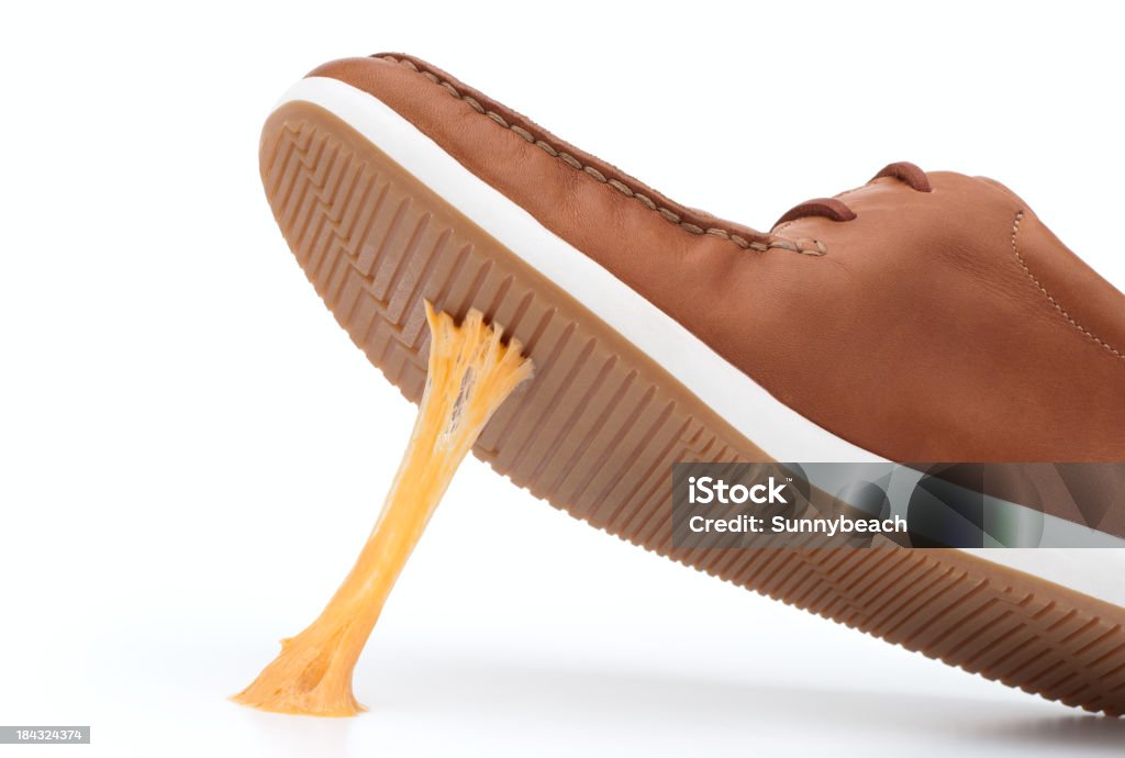 Yellow piece of gum stuck on bottom of brown shoe Chewing gum stuck on a brown shoe against white background Bubble Gum Stock Photo