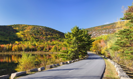A stitched panorama of Beaver Dam Pond, Acadia's Park Loop Road, and nearby mountains covered in Autumn foliage; Acadia National Park, Maine.