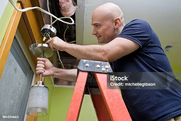 Uomo In Piedi Su Una Scala E Mettendo Una Luce - Fotografie stock e altre immagini di Bricolage - Bricolage, Elettricità, Accessorio per le lampade