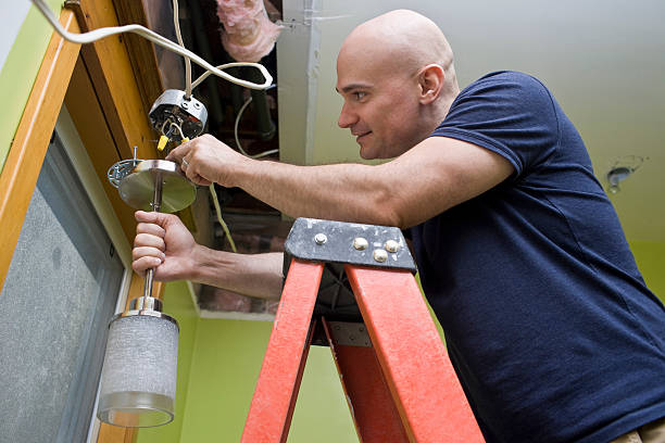 Man standing on a ladder and putting up a light