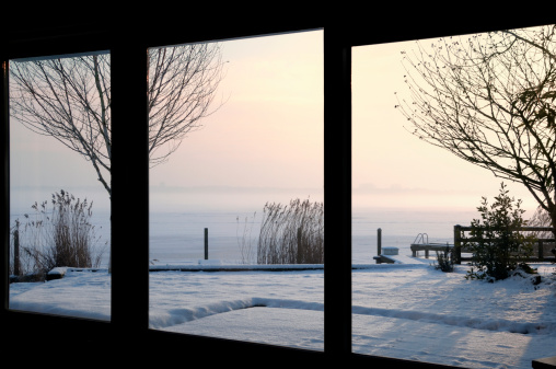 View through the french doors over the frozen lake covered with snow