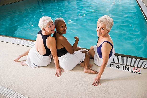 vue arrière de femme senior assis au bord de la piscine - sc0450 photos et images de collection