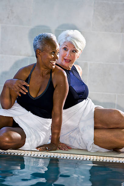 multiraciale femmes âgées assis au bord de la piscine - sc0450 photos et images de collection