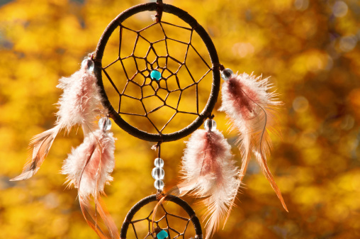 dreamcatcher detail in the evening in front of blurry trees. Indian Summer. 