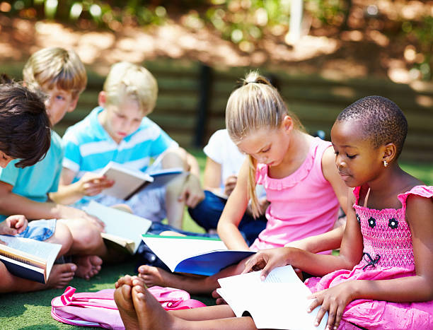 istock Young children sitting on grass and studying 184327202