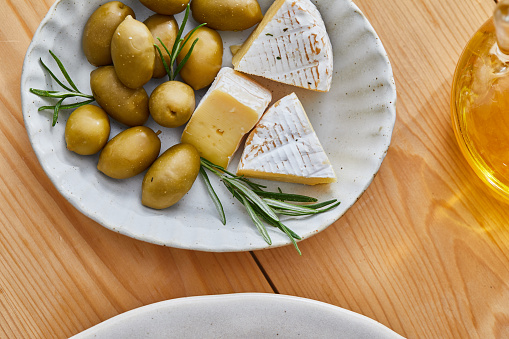 A perfect holiday appetizer plate, made from Camembert cheese, organic olives, rosemary, fresh olive oil, local organic seasoning, herbs and spices. Representing a healthy lifestyle, healthy eating, a wellbeing, modern city life, traditional culture and a perfect brunch gourmet delicatessen.