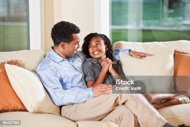 Excitación Chica Con Padre En El Sofá Hablando Foto de stock y más banco de imágenes de Afrodescendiente - Afrodescendiente, Hija, Padre