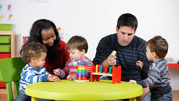 Carers Interacting With Group Of Toddlers At Playtime