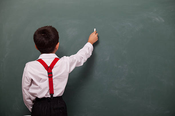 istock Back View Of Little Boy Writing On Blank Blackboard 184328363
