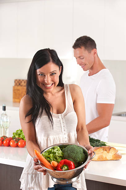 Woman holding a colander of fresh vegetables