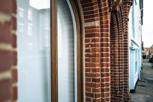 Shallow focus of an arched brick pillar located of the outside of commercial offices down a narrow street. The pavement appears quiet as nearly dusk.