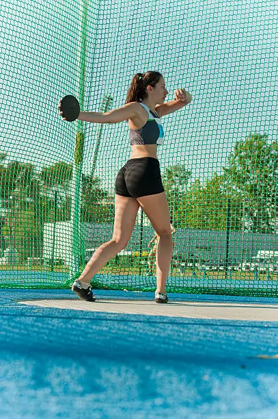 Rear view of young female athlete ready for throwing the discus