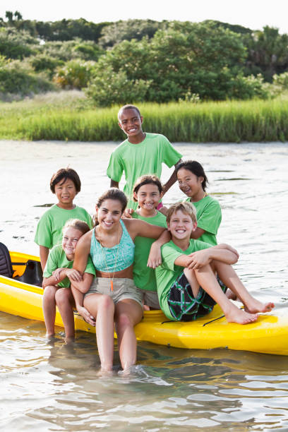 ajudante de colônia de férias de verão e crianças, sentado no caiaque - summer camp child teenager kayak - fotografias e filmes do acervo