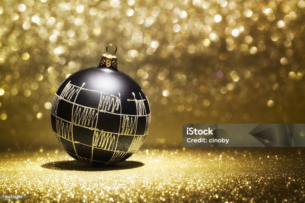 Black Christmas Bauble black christmas bauble in spotlight and selective focus with defocused glitter background Gold - Metal Stock Photo