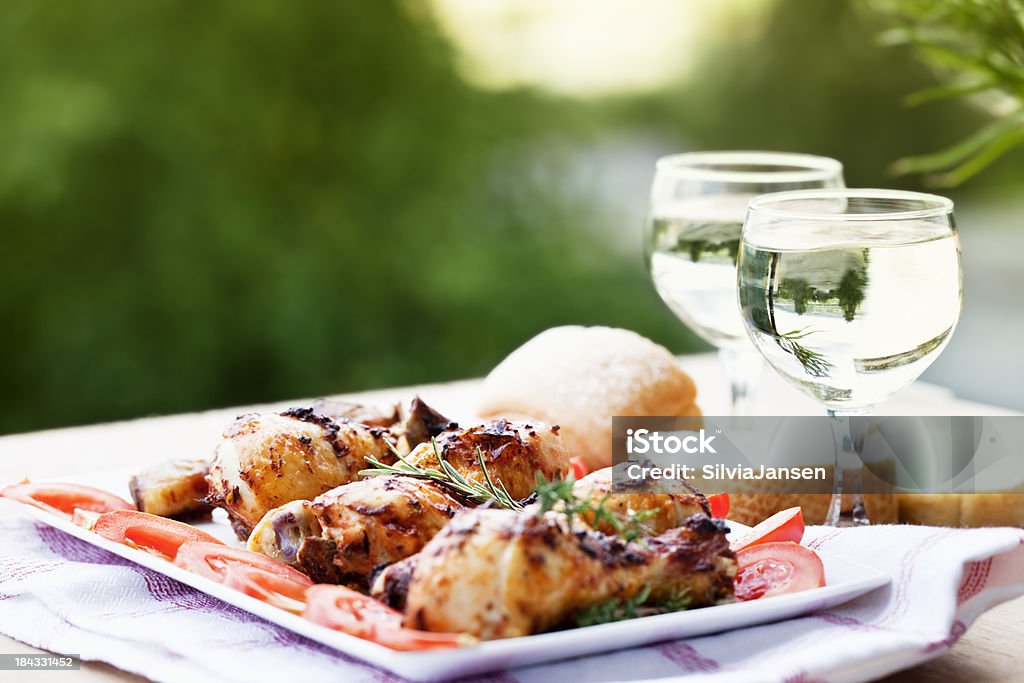 chicken leg wine summer picnic roast chicken legs, decorated with slices of tomato on a white plate, perfect picnic food for  a warm summer evening, 2 glasses with white wine Wine Stock Photo