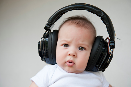 Beautiful smiling baby listens to music with headphones