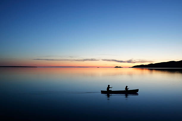 XL twilight canoeing father and son in silhouette conoeing at twilight (XL) canoeing stock pictures, royalty-free photos & images