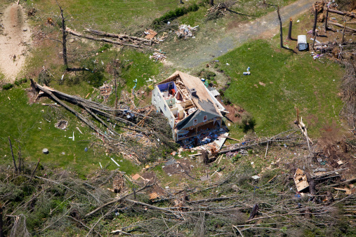 An aerial view of the destruction done by a tornado to a single family house.