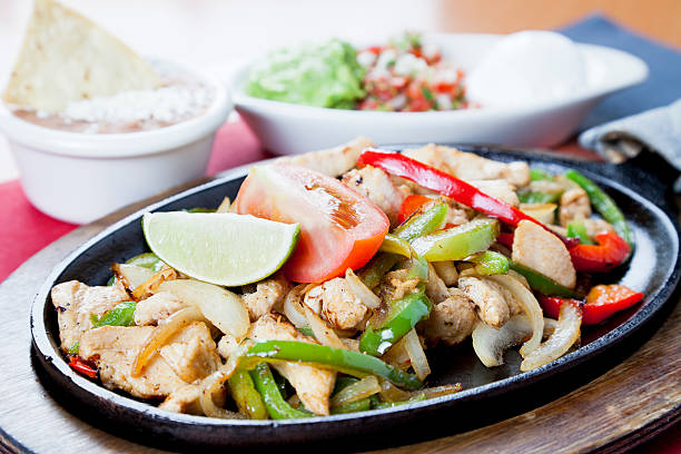 istock Mexican food:  chicken fajitas on a hot cast iron skillet 184334314