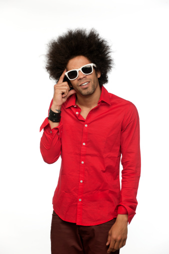 three quarter length shot of a happy man with big afro hair in red shirt and tinted sunglasses looking at the camera on white background