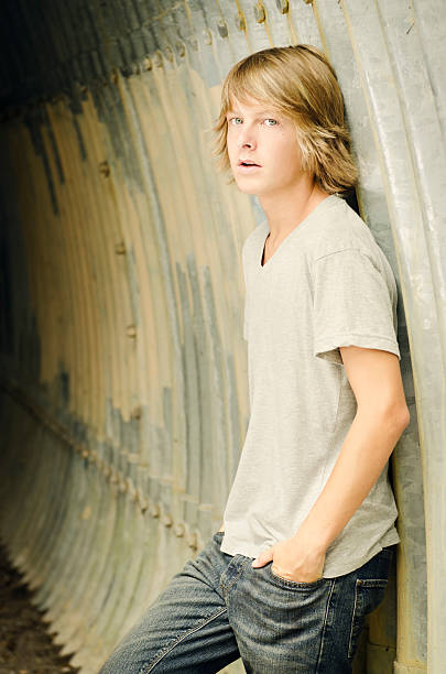 Serious Teen Boy Leaning Against A Tunnel Wall Stock Photo - Download Image  Now - Long Hair, Teenage Boys, Blond Hair - iStock