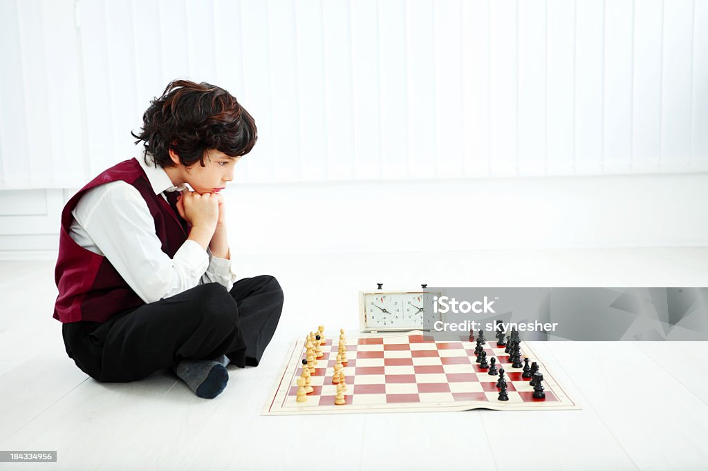 Chłopiec myśli i gra w szachy. - Zbiór zdjęć royalty-free (Białe tło)