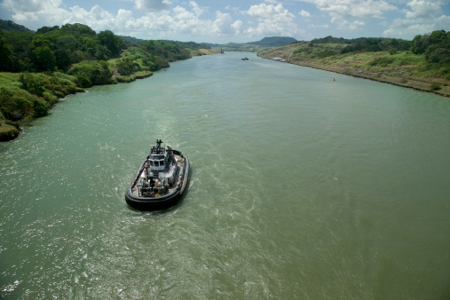 Wide angle view of the Panama Canal. No legible markings on tug. Horizontal shot.