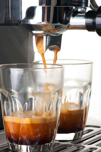 Espresso shot glasses being filled in a coffee machine