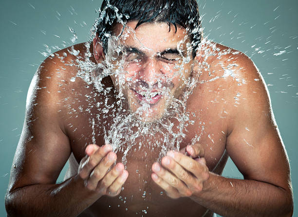 Naked man splashing water on his face