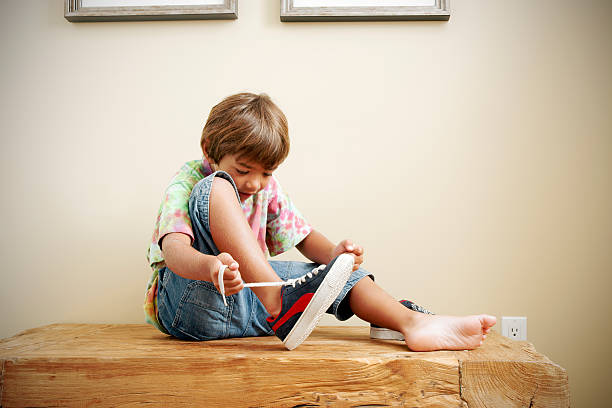 Tying laces A photograph of a little boy tying-up his shoes getting ready to go outside.Please browse: child tied up stock pictures, royalty-free photos & images