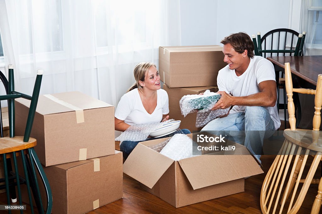 Young couple moving into new home Couple, 20s, moving house, packing or unpacking belongings. Bubble Wrap Stock Photo