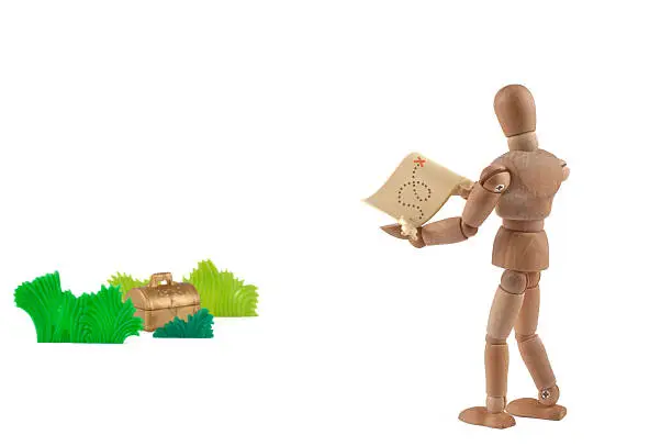 wooden mannequin with map and treasure hidden in gras. Concept for treasure, success, geocache and  a lots of more. be creative too :)