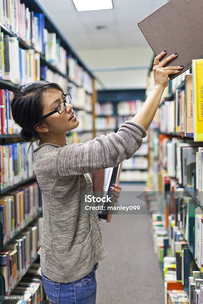 Bella giovane studentessa Cerca i libri nella libreria - Foto stock royalty-free di Biblioteca