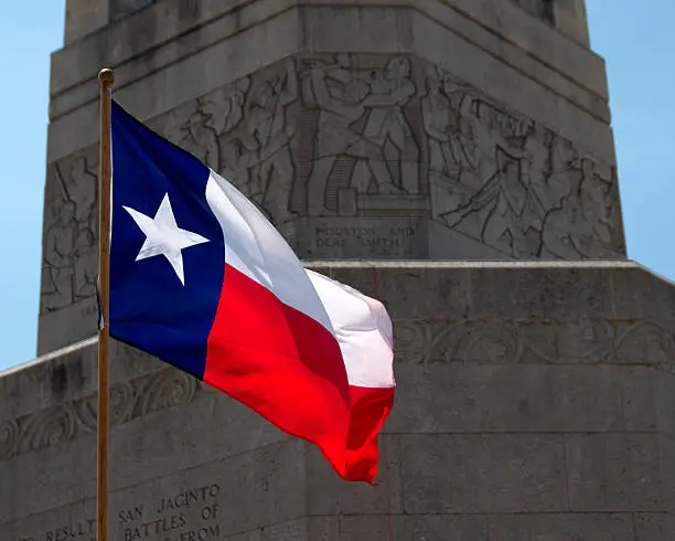 "Texas flag in front of the San Jacinto Battleground monument near Houston, Texas."