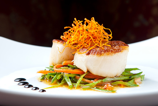 Selective-focus image of Seared Scallops on a bed of vegetables