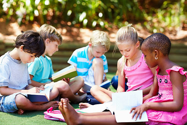 istock Multi ethnic children sitting on grass and studying 184340504