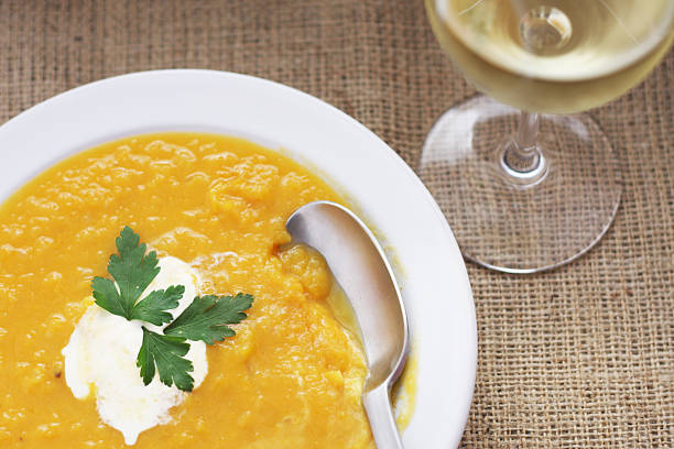 Pumpkin Soup and glass of white wine on burlap tablecloth