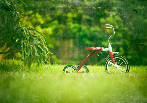 vintage red kid tricycle  in a backyard - grunge textures overlay
