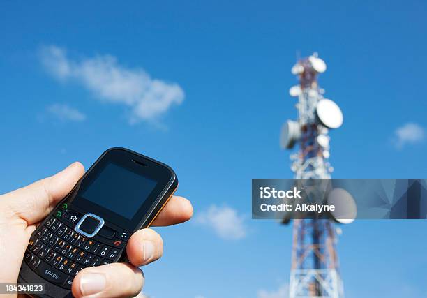 Holding A Mobile Phone And Communication Tower Stock Photo - Download Image Now - Black Color, Blue, Business