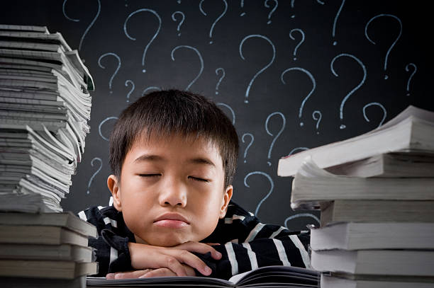 istock Little boy sitting amidst a stack of books 184341993