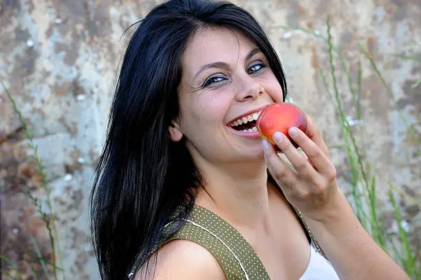 "Beautiful young farm girl enjoying a freshly picked necatrine peach. Western Cape, South Africa."