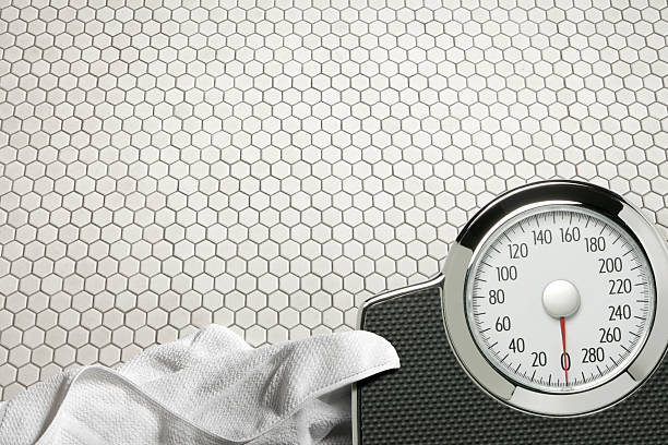 istock Scale and bath towel on bathroom floor 184343463