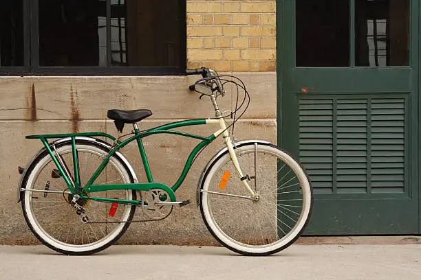 Photo of Vintage Bicycle Leaning Against Brick, Concrete Wall and Green Door