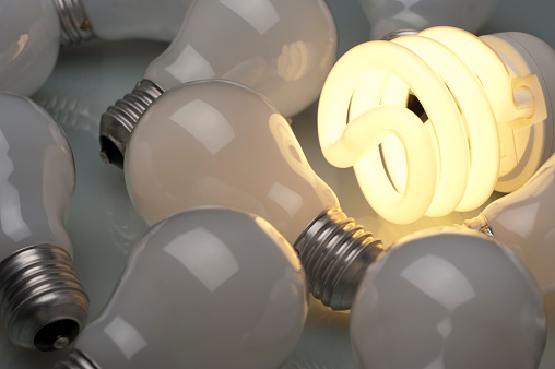 Lit Energy efficient light bulb in a group of old light bulbs