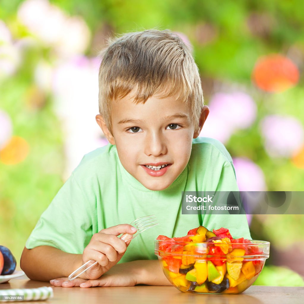 Heureux petit garçon manger Salade de fruits frais - Photo de Enthousiaste libre de droits