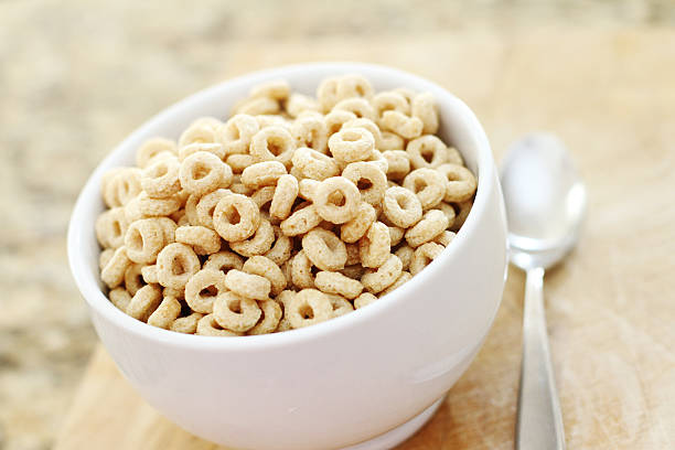 Oat cereal in loop shape in white bowl with spoon next to it stock photo