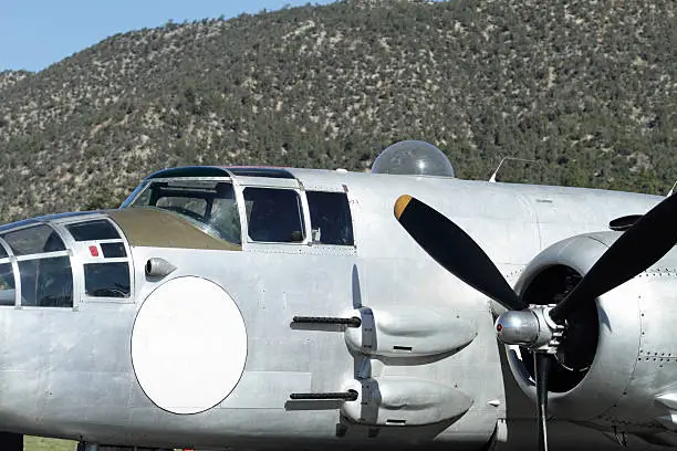 Restored WWII era North American B-25J bomber on the tarmac at Big Bear Airport in California with a blank white circle on fuselage for copy.