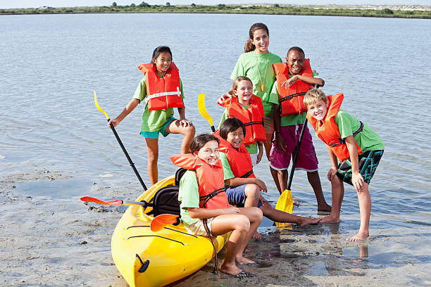 animateur de colonie de vacances d'été et les enfants en kayak - kayak canoeing canoe lake photos et images de collection