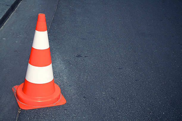 istock Bright Orange and White Traffic Cone Dark Asphalt 184345438